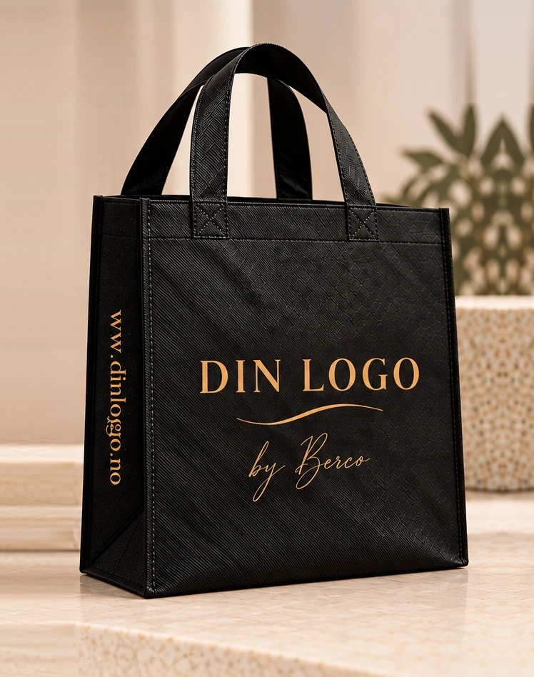 Sort gjenbrukspose i non woven med preget mønster og lange hanker. Foran står «Din logo by Berco» i gull, som eksempel på trykk.